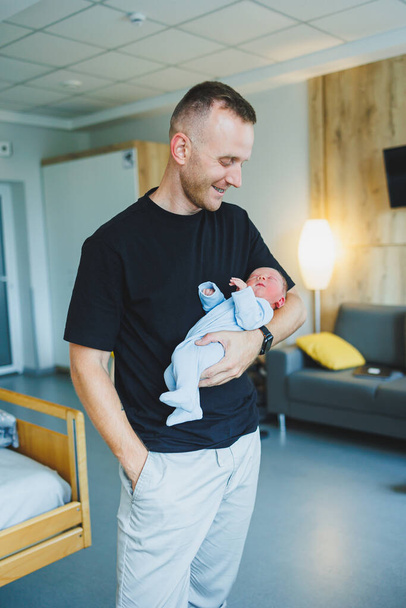 Niño recién nacido en los brazos de su padre, acostado en sus brazos vista superior de cerca. Un hombre sostiene a un niño pequeño. Un estilo de vida saludable. Paternidad - Foto, Imagen