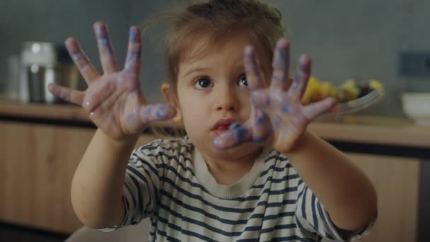 Niña mostrando sus palmas sucias con plastilina azul a la cámara. Guardería. Niños creativos moldeando en casa. - Imágenes, Vídeo