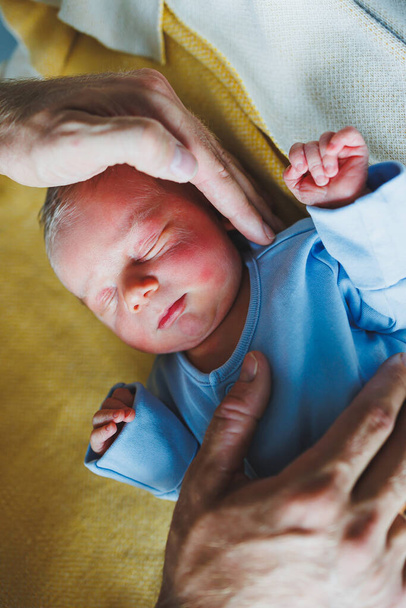 Újszülött kisfiú az anyja és az apja karjaiban, a karjaikon fekve, közelről. A fiatal szülők tartják a kisbabájukat. Egészséges életmód. Apaság - Fotó, kép