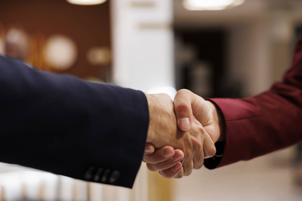 Entrepreneurs agreeing upon collab together, successful important meeting at hotel abroad. Business professionals shaking hands to mark the beginning of a fruitful partnership. Close up. - Photo, Image