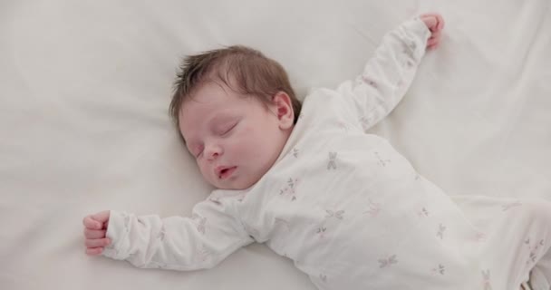Bébé mignon, endormi et nouveau-né sur un lit dans une maison dans la chambre à coucher pour se reposer et rêver. Vue fatiguée, douce et de dessus du nourrisson, de l'enfant ou de l'enfant faisant une sieste le matin dans la crèche à la maison familiale - Séquence, vidéo