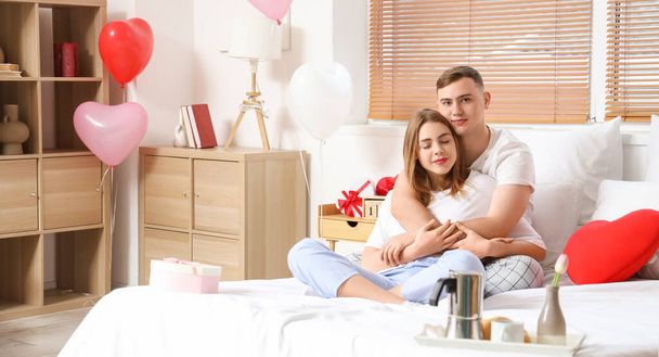 バレンタインデーに寝室に座っている若いカップル - 写真・画像
