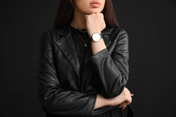 Stilvolle junge Frau mit Armbanduhr auf schwarzem Hintergrund - Foto, Bild