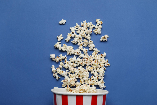 Emmer met lekkere popcorn op blauwe achtergrond - Foto, afbeelding