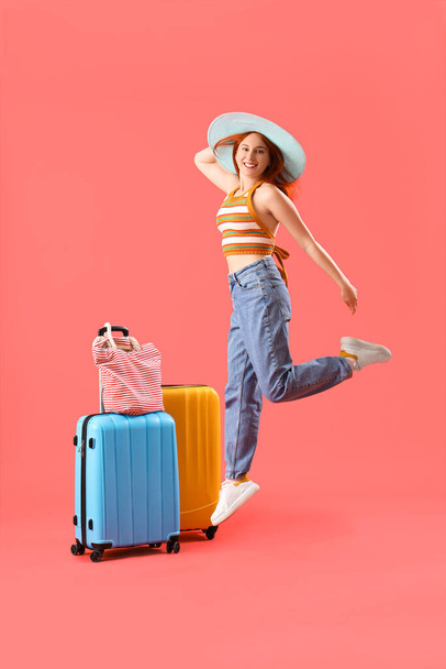 Saltando turista femenina con equipaje sobre fondo rojo - Foto, Imagen