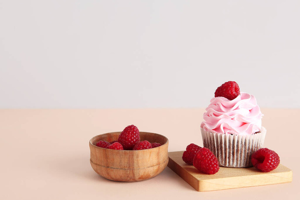 Tasty raspberry cupcake and fresh berries on beige background - Photo, Image