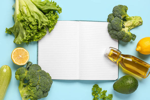 Zusammensetzung mit leerem Rezeptbuch, Olivenöl und Gemüse auf farbigem Hintergrund - Foto, Bild