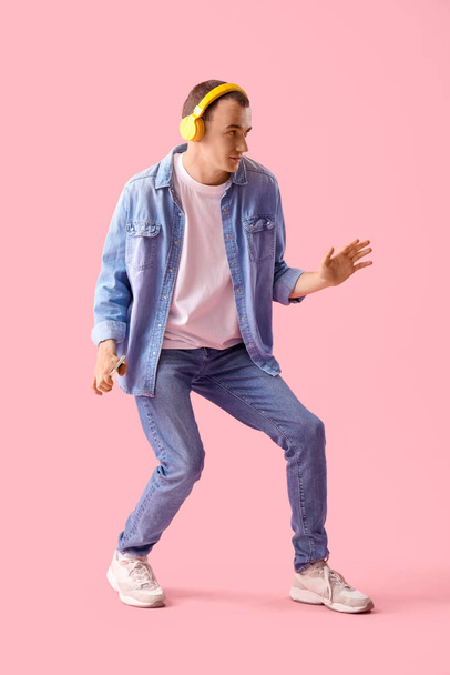 Nuori mies kuulokkeet matkapuhelin tanssia vaaleanpunainen tausta - Valokuva, kuva