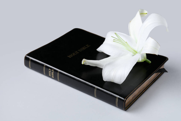Όμορφο λουλούδι κρίνο και Αγία Γραφή σε γκρι φόντο - Φωτογραφία, εικόνα