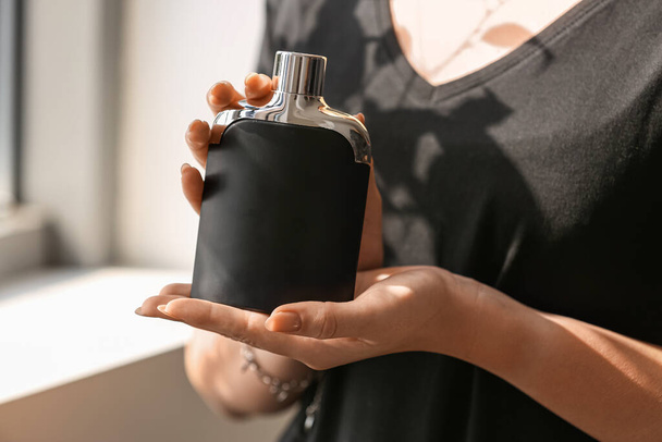Жіночі руки з пляшкою елегантних парфумів біля вікна, крупним планом - Фото, зображення