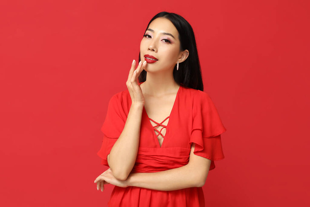 Beautiful Asian woman with stylish makeup on red background - Photo, Image