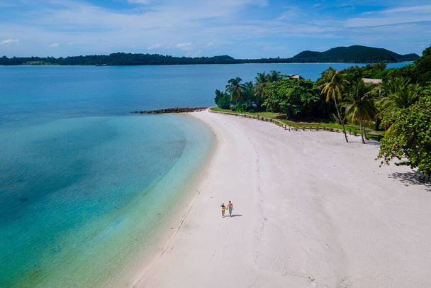 couple walking at the beach of Koh Kham Trat Thailand, aerial view of the tropical island near Koh Mak Thailand. white sandy beach with palm trees and big black boulder stones in the ocean - Foto, Imagen