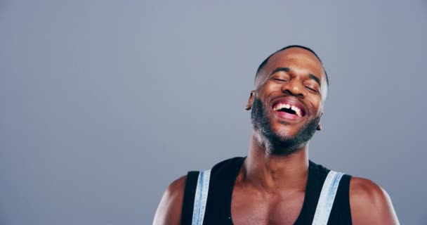 Face, happy and black man laughing in studio for humor, joke and good mood on grey background. Portrait, guy and smile with cheerful personality for comedy, expression or funny reaction to silly news. - Footage, Video