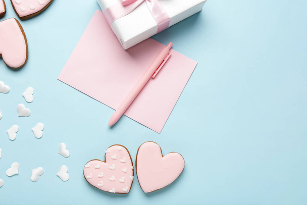 Szív alakú sütik ajándékdobozzal és papírral kék háttérrel. Valentin-napi ünneplés - Fotó, kép