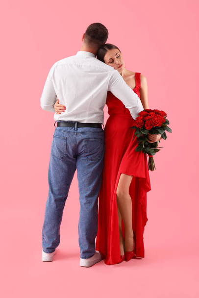 Schönes Paar mit einem Strauß Rosen auf rosa Hintergrund. Valentinstag-Feier - Foto, Bild