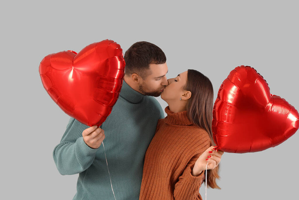 Casal encantador com balões em forma de coração no fundo cinza. Celebração do Dia dos Namorados - Foto, Imagem
