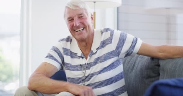 Szczęśliwy, twarz i starszy mężczyzna na kanapie zrelaksować, pewny siebie i pozytywne nastawienie w swoim domu z dobrym nastroju. Uśmiech, portret i starszy mężczyzna na emeryturze w salonie z wolnością weekendową. - Materiał filmowy, wideo