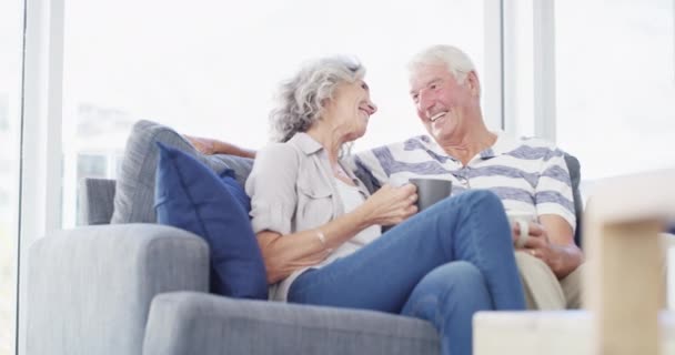 Χαλαρώστε, αγάπη και ηλικιωμένο ζευγάρι σε έναν καναπέ με διάλειμμα για καφέ, σύνδεση και ειδύλλιο στο σπίτι μαζί. Υποστήριξη, ευγνωμοσύνη και οι ηλικιωμένοι αγκαλιάζουν σε ένα σαλόνι απολαμβάνουν σχέση, δεσμό ή συνταξιοδότηση. - Πλάνα, βίντεο