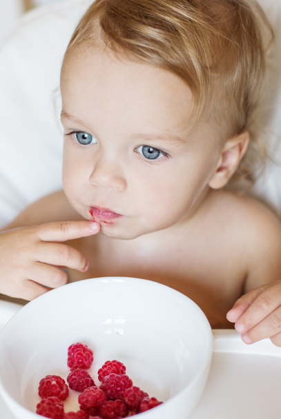 Μικρό παιδί μωρό τρώει σμέουρα που κάθεται στο τραπέζι - Φωτογραφία, εικόνα