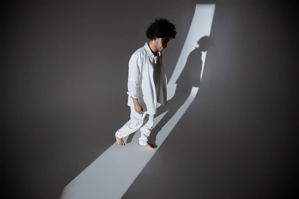Full shot of young man stepping from shadow into strip of light - Fotoğraf, Görsel