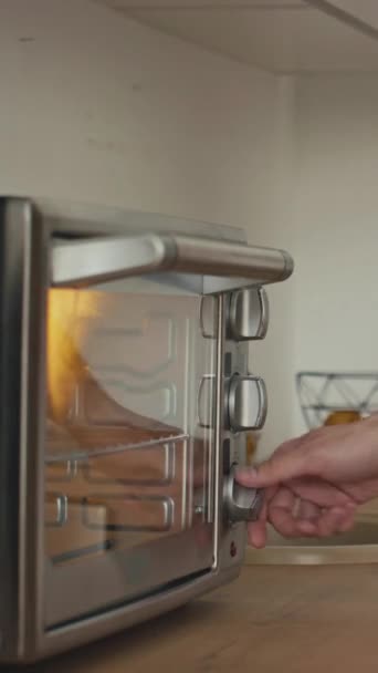 tiro lateral facada vertical de homem irreconhecível desligar forno torradeira e tomar refeição quente na cozinha moderna - Filmagem, Vídeo