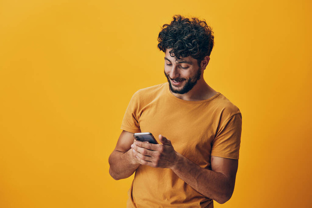 Hombre modelo chico móvil estudiante sonrisa estilo gadget feliz amarillo guapo comunicación retrato teléfono en línea smartphone joven tecnología - Foto, imagen