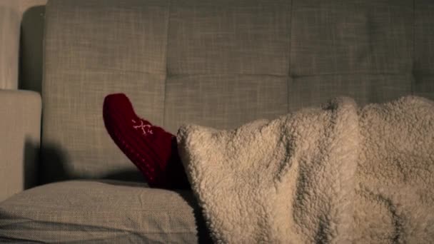 Pieds dans les chaussettes de Noël sur canapé avec couverture confortable tir moyen 4k slow motion mise au point sélective - Séquence, vidéo