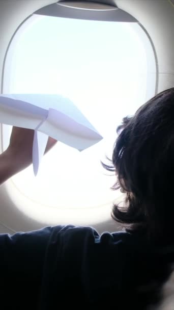 jonge jongen met papier vliegtuig venster. - Video