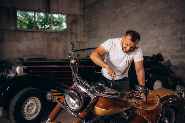 ガレージでレトロバイクを修理する男 - 写真・画像