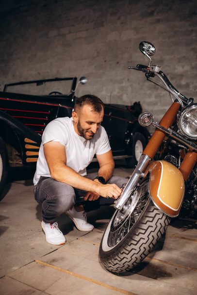 Мужчина ремонтирует ретро мотоцикл в гараже - Фото, изображение