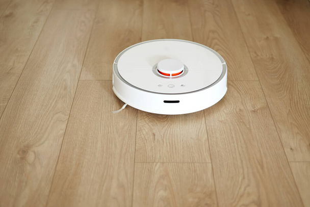 Bezdrátový autonomní robotický vysavač vysává podlahu s moderními dlaždicemi v obývacím pokoji. Samohybný čistící robot. Systém čištění podlah. Domácí dálkové ovládání spotřebičů - Fotografie, Obrázek