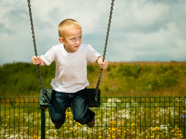 Little blonde boy child having fun on a swing outdoor - Photo, image
