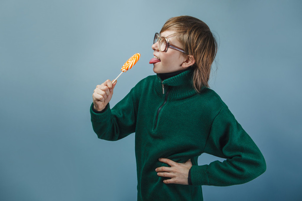 Europeu-olhando menino de dez anos de óculos lambendo uma pirueta
 - Foto, Imagem
