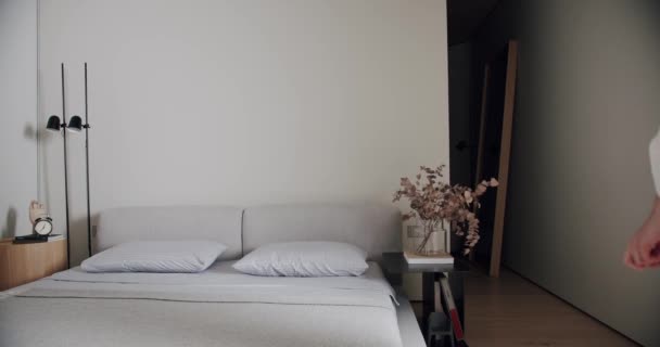 Κρεβατοκάμαρα σε μινιμαλιστικό διαμέρισμα σε λευκούς τόνους, με μοντέρνα μεγάλη εικόνα και μαύρη λάμπα. άνετο μινιμαλιστικό εσωτερικό. κομψότητα σπίτι, δωμάτιο ξενοδοχείου, μοντέρνα έπιπλα, σύγχρονο σχεδιασμό σπιτιού - Πλάνα, βίντεο