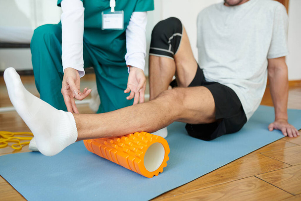 Patient or rehabilitation center using myofascial roll to release muscle tension in calf - Photo, Image
