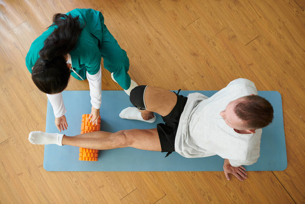 Человек с травмой ноги учится делать миофасциальное освобождение с помощью пенопласта - Фото, изображение