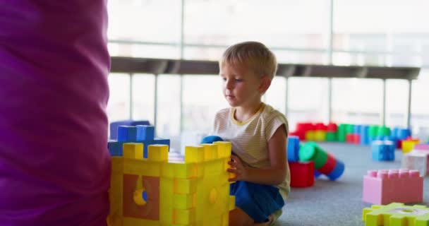 Een kind speelt met speelgoed bouwstenen in een kinderspeelplaats of kleuterschool. Concept van vroege ontwikkeling, recreatie en entertainment. Hoge kwaliteit 4k beeldmateriaal - Video