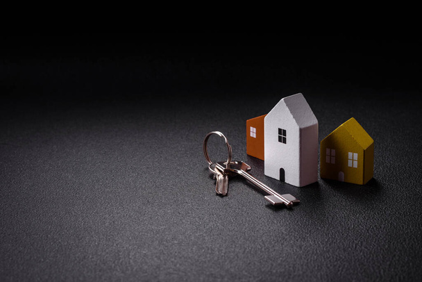 Malý dřevěný dům a klíče jako nápad pro investování do svého domova a dosažení cíle nákupu nemovitostí. Pozadí pro váš nápad - Fotografie, Obrázek