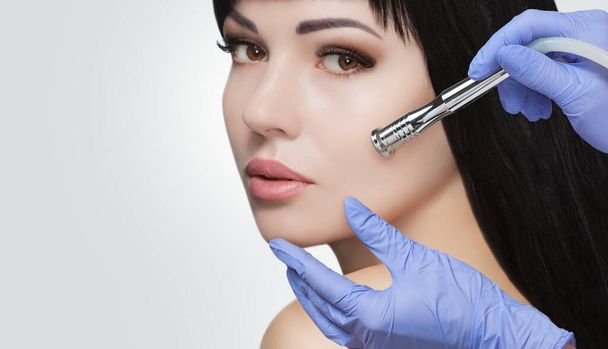 Hay una mujer, que está haciendo el procedimiento Microdermoabrasión de la piel facial en un salón de belleza. Cosmetología y cuidado profesional de la piel. - Foto, imagen