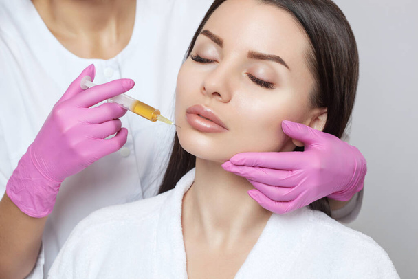 Kosmetolog robi prp terapii na twarzy pięknej kobiety w salonie piękności. W warunkach in vitro jest gotowe do wstrzyknięcia osocze krwi. Koncepcja kosmetyczna. - Zdjęcie, obraz