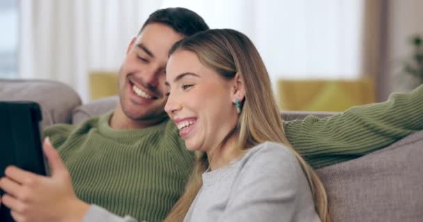 Home, love and couple on a couch, tablet and streaming movies with social media, email and conversation. Lounge, man or woman on a sofa, technology or app for fun, talking or search internet for info. - Footage, Video