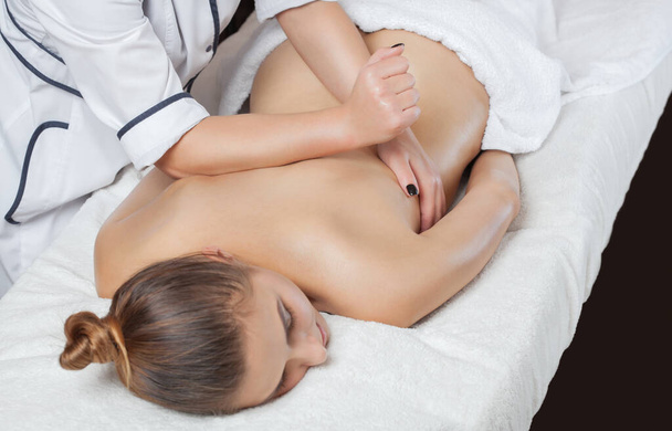 Masajista hace un masaje relajante en el cuello, hombros, espalda y clavículas de una joven hermosa mujer en un spa. Cosmetología y concepto de masaje. - Foto, imagen