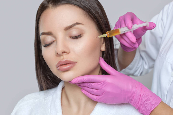 Косметолог проводит prp-терапию на лице красивой женщины с чистой кожей в салоне красоты. Концепция косметологии. - Фото, изображение