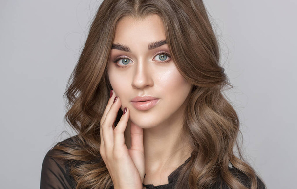 Portrait of a beautiful woman with long eyelashes, beautiful fresh nude make-up, thick eyebrows and with clean skin in a beauty salon. Eyelash extensions. Face close-up.Make-up and cosmetology concept - Photo, Image