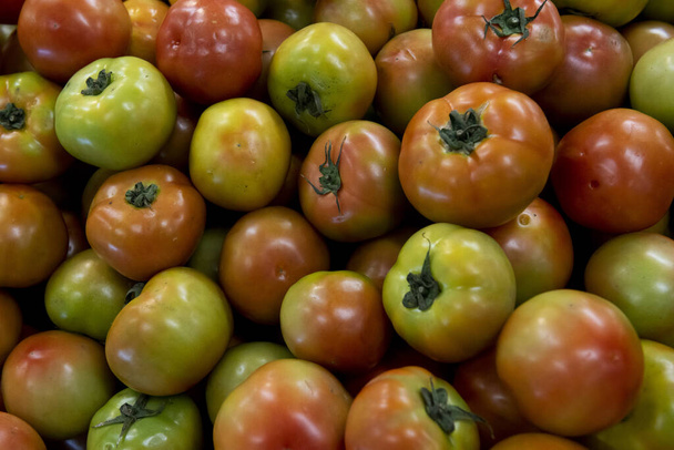 Σωρός από πράσινες και κόκκινες ντομάτες στην αγορά. - Φωτογραφία, εικόνα