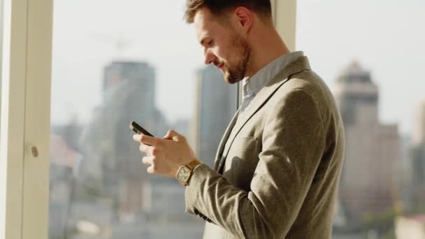 Detailní záběr mužských rukou držících moderní smartphone. Podnikatel kráčí, zatímco píše na svém mobilním telefonu. Luxusní hodinky na mužské ruce v popředí. Klasický černý oblek. Obchod - Záběry, video