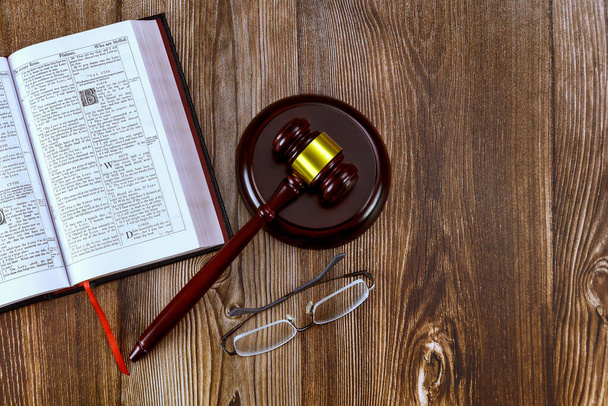 24 ДЕКАБРЯ 2023 Вашингтон, США. Библия открыта для изучения на деревянном столе с очками судьи молотка - Фото, изображение