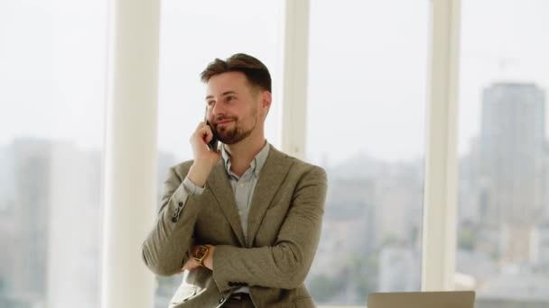 Mladý obchodník pracující v úřadu. Šťastný muž mluví s někým telefonem. Je šťastný. Muž volá své ženě, aby si promluvila o plánech na dovolenou. Vysoce kvalitní 4K záběry - Záběry, video