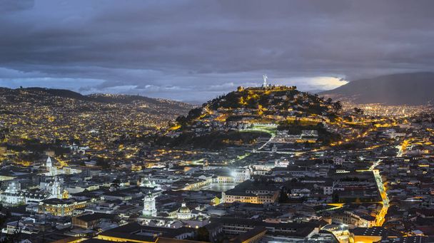 Панорамный вид на колониальный центр Кито ночью. Площадь Сан-Франциско доминирует над холмом Панесильо и статуей Виргена Кито. Также иллюминация, церковь Ла Мерсед и церковь Ла Компания - Фото, изображение