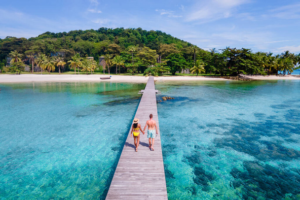 pareja caminando en un muelle de madera en el océano de Koh Kham Trat Tailandia una isla tropical cerca de Koh Mak Tailandia. playa de arena blanca con palmeras - Foto, Imagen